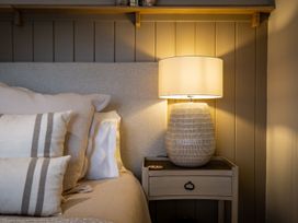A bedroom with a bed and a lamp on a nightstand at Calm Waters Luxury Beach House in Bridlington