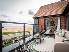 A balcony with seating and a view of the beach at Calm Waters Luxury Beach House in Bridlington