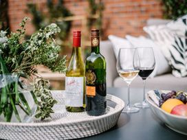 Wine bottles and glasses on a table with fruit at Calm Waters Luxury Beach House in Bridlington