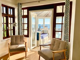A sunroom with chairs and large windows at Crows Nest Dawlish