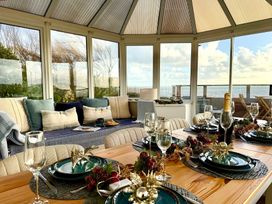 A conservatory with a dining table set for a meal at Crows Nest Dawlish