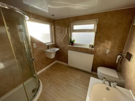 A bathroom featuring a shower, wash basin, toilet, and radiator at Crows Nest Dawlish