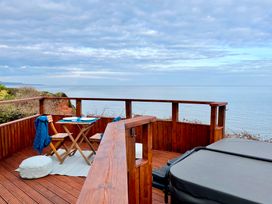 An outdoor space with a table and chairs overlooking the ocean at Crows Nest Dawlish
