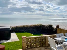 An outdoor area with a table and chairs overlooking the ocean at Crows Nest Dawlish in Dawlish