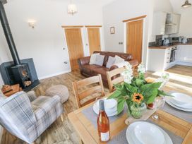 A living room with a sofa a dining table and kitchen appliances at Cadno in Llanybydder