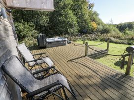 An outdoor area with a deck, hot tub, and chairs at Cadno in Llanybydder