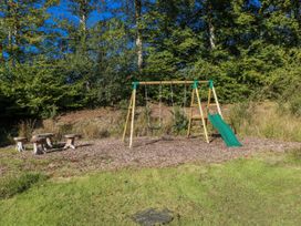 A playground with swings and slide in an outdoor area at Cadno Llanybydder