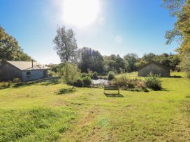 An outdoor area with two buildings and a pond at Cadno in Llanybydder