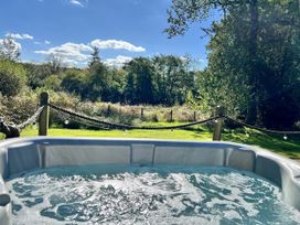 A hot tub with water and trees in the background at Cadno Aber near Llanybydder