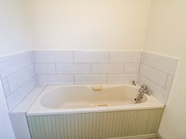 A bathroom with a bathtub and wall tiles at Shamrock House