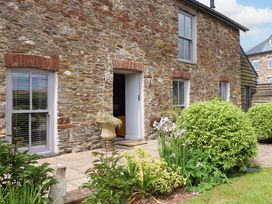 An outdoor view of a stone building with windows and a door at Duke's Barn Blackawton near Dartmouth