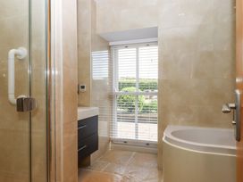 A bathroom with a shower, bathtub, sink and window at Duke's Barn Blackawton near Dartmouth