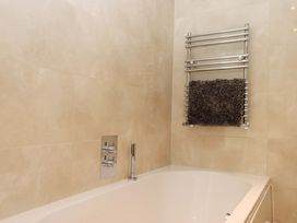 A bathroom with a bathtub and towel rack at Duke's Barn in Blackawton near Dartmouth