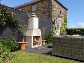 A garden with a fireplace and a couch at Duke's Barn in Blackawton near Dartmouth