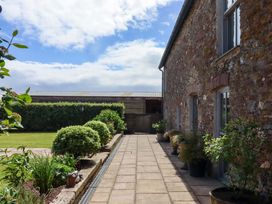 A pathway beside a stone building with planters at Duke's Barn Blackawton near Dartmouth