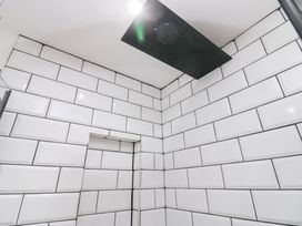 A bathroom with showerhead and tiled walls at Catbells in Windermere