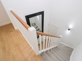 A staircase with a railing and a mirror in the stairway at Catbells in Windermere