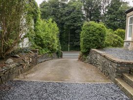 A gravel driveway with stone walls and bushes at Catbells in Windermere