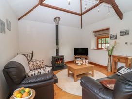 A living room with a wood burning stove and television at The Coach House in Tavistock