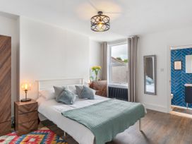 A bedroom with a bed and nightstand with lamp at The Sundial in St Austell