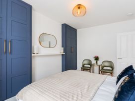 A bedroom with a bed, wardrobe, chairs and a mirror at The Sundial in St Austell