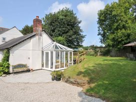 A garden with a conservatory and bench at Upper Court Cottage in Broad Langdon near Wainhouse Corner