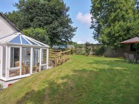A garden with a conservatory and seating area at Upper Court Cottage Broad Langdon near Wainhouse Corner