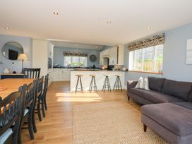 A kitchen and dining area with a dining table and bar stools at Criw in Bryncroes near Sarn Meyllteyrn
