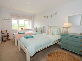 A bedroom with two beds and a chair at Criw in Bryncroes near Sarn Meyllteyrn