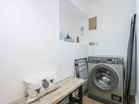 A laundry room with a washing machine and ironing board at Criw in Bryncroes near Sarn Meyllteyrn