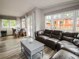 A living room with a sofa and dining area at Owls Nook Lodge in Langdale 9, White Cross Bay near Windermere