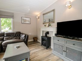 A living room with a sofa and television at Owls Nook Lodge, Langdale 9, White Cross Bay near Windermere