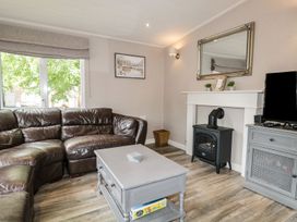 A living room with a sofa, coffee table, and fireplace at Owls Nook Lodge, Langdale 9, White Cross Bay near Windermere