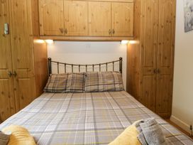 A bedroom with a bed and wooden storage at Owls Nook Lodge, Langdale 9, White Cross Bay near Windermere
