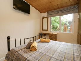 A bedroom with a bed and television at Owls Nook Lodge, Langdale 9, White Cross Bay near Windermere