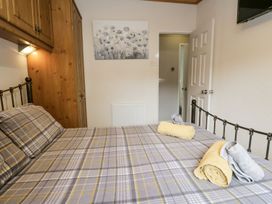 A bedroom with a bed, towels, and wardrobe at Owls Nook Lodge, Langdale 9, White Cross Bay near Windermere