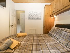 A bedroom with a bed, towels on the bed, and a wardrobe at Owls Nook Lodge, Langdale 9, White Cross Bay near Windermere