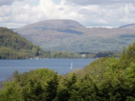 A view of mountains and a lake with a sailing boat at Owls Nook Lodge, Langdale 9, White Cross Bay near Windermere