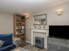 A living room with a shelf, mirror, and fireplace at Owls Nook Lodge, Langdale 9, White Cross Bay near Windermere