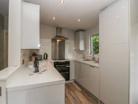 A kitchen with cabinets, sink, and oven at Owls Nook Lodge in Langdale 9, White Cross Bay near Windermere
