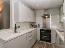 A kitchen with a cooker and wine glasses at Owls Nook Lodge Langdale 9, White Cross Bay near Windermere