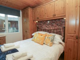A bedroom with a bed and wardrobe at Owls Nook Lodge Langdale 9, White Cross Bay near Windermere
