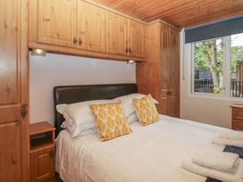 A bedroom with a bed and wooden furniture at Owls Nook Lodge, Langdale 9, White Cross Bay near Windermere