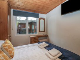 A bedroom with a bed and television at Owls Nook Lodge, Langdale 9, White Cross Bay near Windermere