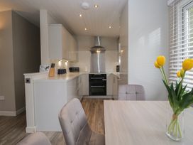 A kitchen with cooking appliances and a dining table at Owls Nook Lodge, Langdale 9, White Cross Bay near Windermere