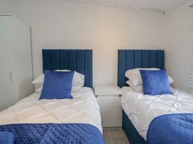 A bedroom with two twin beds and a bedside table at Owls Nook Lodge, Langdale 9, White Cross Bay near Windermere