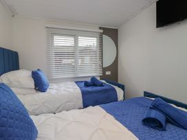 A bedroom with two beds and a television at Owls Nook Lodge Langdale 9, White Cross Bay near Windermere