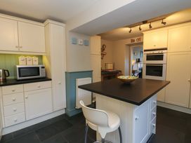 A kitchen with cabinets and a microwave at Zenobia in New Quay