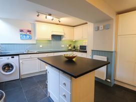A kitchen with a sink, washing machine, and cupboards at Zenobia in New Quay