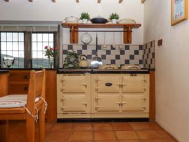 A kitchen with a stove and a shelf with cookware at Higher Wadden Farm in Southleigh